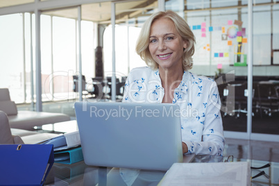 Portrait of smiling entrepreneur working on laptop at office