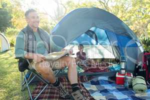 Man reading the map outside the tent at campsite