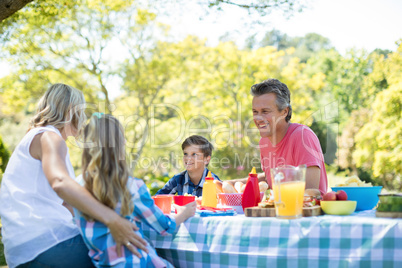 Happy family interacting with each other while having meal in park