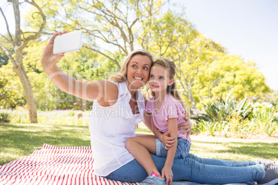 Mother and daughter taking selfie on mobile phone in park