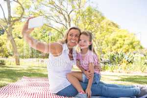 Mother and daughter taking selfie on mobile phone in park