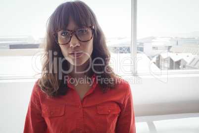 Serious female designer standing by window in office