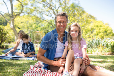 Daughter sitting on fathers lap in park