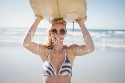 Portrait of happy woman carrying surfboard at beach