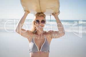 Portrait of happy woman carrying surfboard at beach
