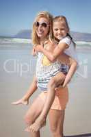 Portrait of happy mother piggybacking her daughter at beach