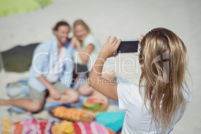 Rear view of girl photographing her parents at beach