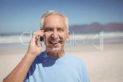 Portrait of senior man talking on mobile phone at beach