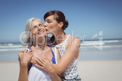 Young woman kissing her mother at beach