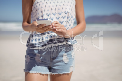 Mid section of woman using mobile phone at beach