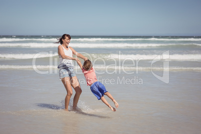 Happy mother enjoying with son on shore at beach