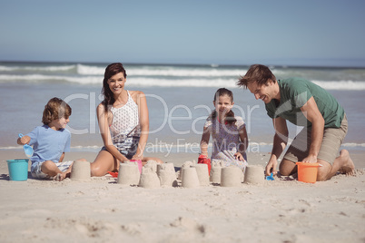 Happy family making sand castle at beach
