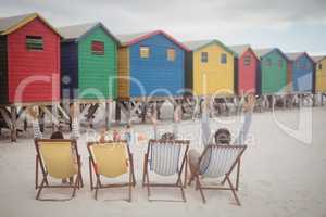 Family with arms raised resting on lounge chairs