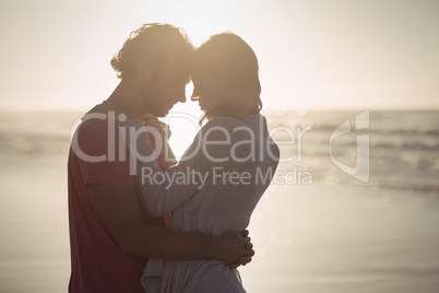 Side view of couple embracing at beach