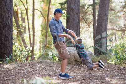 Father swinging little son in forest