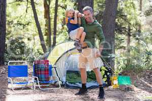 Playful father carrying son by tent at campsite