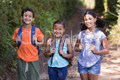 Smiling friends carrying backpack at natural parkland
