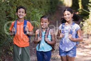 Smiling friends carrying backpack at natural parkland