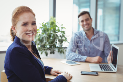 Portrait of smiling executives sitting at desk