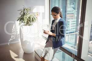 Attentive businesswoman using mobile phone in corridor