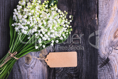 bouquet of fresh lilies of the valley on a gray wooden surface