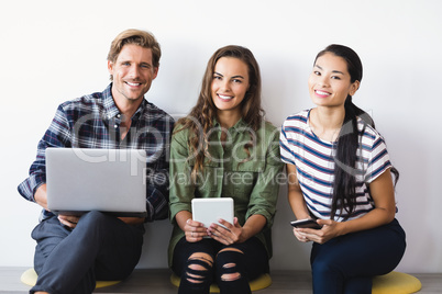 Portrait of business people sitting against wall