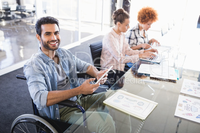 High angle portrait of smiling businessman using digital tablet while sitting on wheelchair