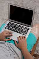 Mid section of man using laptop at beach