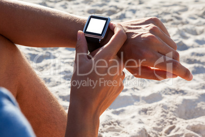 Man checking his smartwatch on the beach