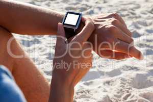 Man checking his smartwatch on the beach