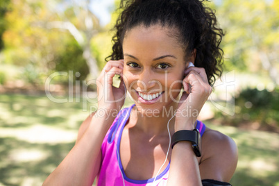 Close-up of smiling jogger woman adjusting her headphones