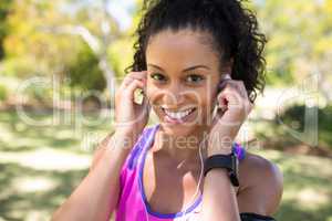 Close-up of smiling jogger woman adjusting her headphones