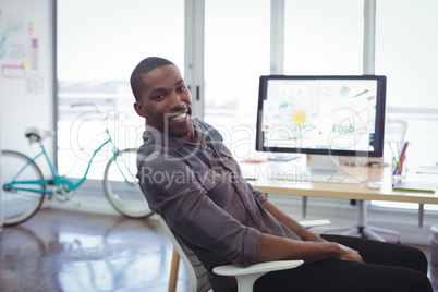 Smiling businessman sitting in brightly lit office