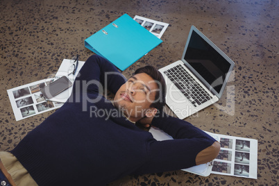 Thoughtful businessman lying by laptop and photographs at office
