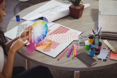 Businesswoman holding colour swatch at office desk