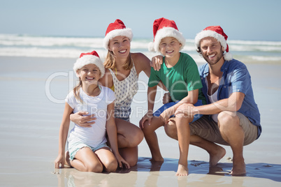 Portrait of smiling family wearing Santa hat at beach