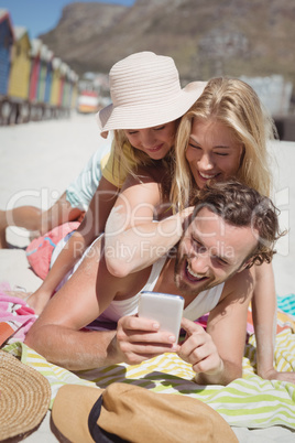 Happy family taking selfie while lying on picnic blanket at beach