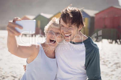 Cheerful woman with son taking selfie at beach