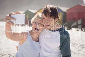 Cheerful woman with son taking selfie at beach