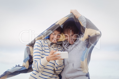Happy young couple using mobile phone during winter