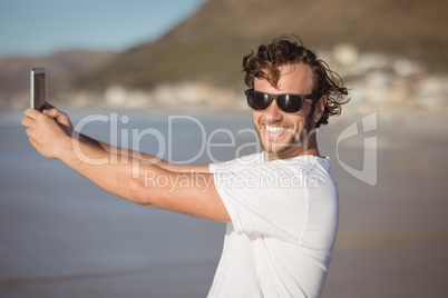 Portrait of smiling man taking selfie at beach