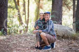 Full length portrait of smiling father and son in forest