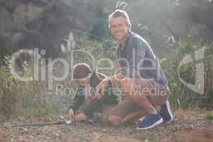 Father sitting by son with fishing rod in forest