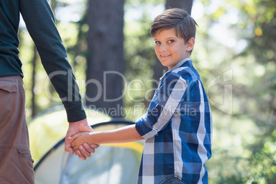 Smiling boy with father hiking in forest
