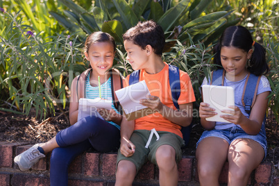 Girl using digital tablet while friends discussing over book