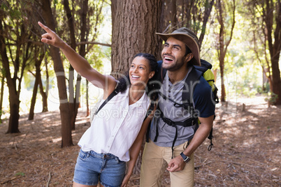 Happy woman pointing to man in forest