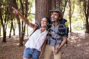 Happy woman pointing to man in forest