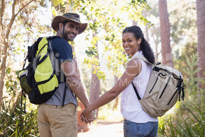 Rear view portrait of couple holding hands in forest