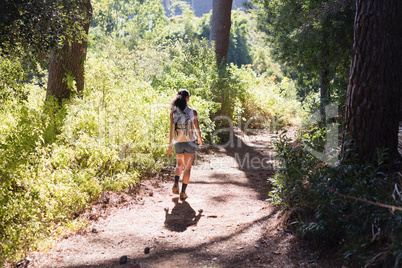 Rear view of woman hiking on trail in forest