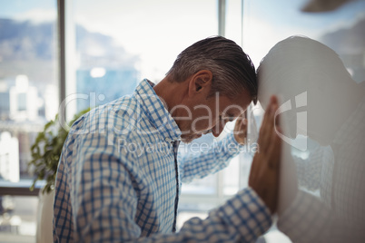 Sad executive leaning on wall